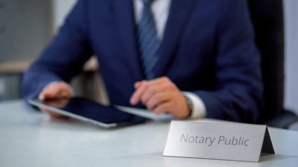 Male notary public viewing files on tablet, checking documents for notarization