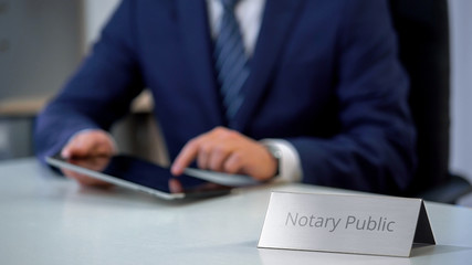 Young notary public working on tablet pc, preparing administrative documents - obrazy, fototapety, plakaty