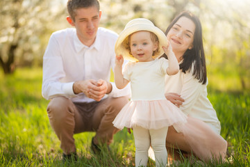 Love, happy family on vacation in a blooming garden in spring, summer. Cheerful mood and warm atmosphere