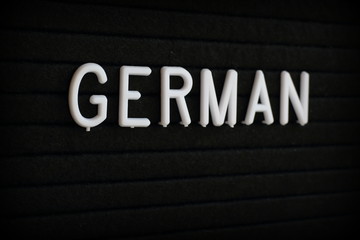 The word German in white plastic letters on a black notice board 