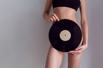 Beautiful girl in underwear, holding an LP microgroove vinyl record on bright background