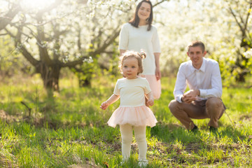 Cheerful family walks in the park with the rays of the sun. Springtime mood blooming gardens