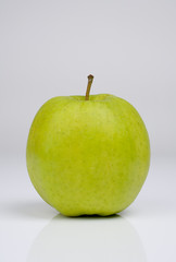 Grüner Apfel vor hellgrauem Hintergrund im Hochformat