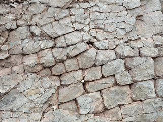 Broken rock in a cliff face. The rock is broken into rectangular shapes, and is weathered and erroded.