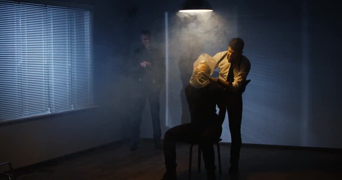 Criminals torturing caught men in dark room