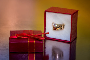 Golden ring in red gift box on golden background