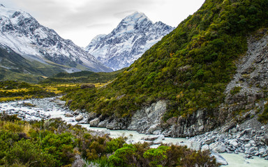 Obraz premium Scenic landscape view of Hooker Valley, Aoraki/Mount Cook National Park, South Island of New Zealand. Snow covered mountains. Tourist (backpackers) popular hiking or walking attraction/destination.