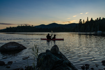 silhouette of man and dog in kayak at sunset