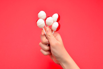 Lollipop in female hand on red background. Space for text or design.