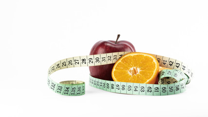 Dietary concept. Red apple with half orange and measuring tape isolated on white background.