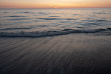 Fototapeta na wymiar Long exposure of waves on beach at sunset