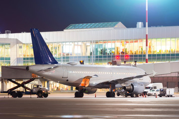 Night look at the terminal with preparing for departure passenger aircraft