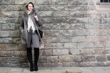Fototapeta na wymiar girl in hood standing near stone wall