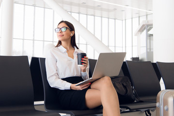 Female executive with suitcase in work related business trip waiting for her flight in an airport