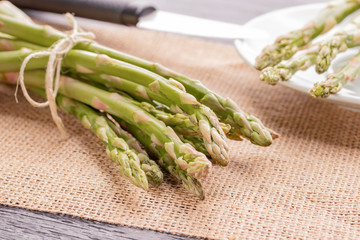 Fresh green asparagus on the table and in a white plate with a shiny knife.
