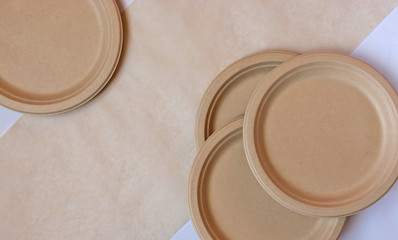 Stack of natural plant paper plates on paper background. Plastic free concept. Copy space