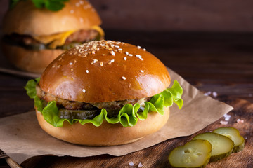 homemade hamburger with beef and cucumbers on wooden background