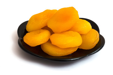 Dried apricots on a black plate, image on a white isolated background_