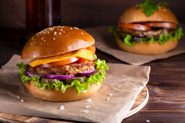 two homemade hamburgers with beef and cucumbers on wooden background