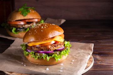 two homemade hamburgers with beef and cucumbers on wooden background