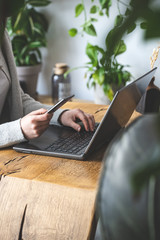 Woman holding cellular in hands and using her laptop