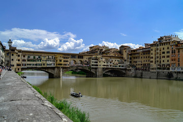 Obraz premium The Ponte Vecchio is a medieval stone closed-spandrel segmental arch bridge over the Arno River, in Florence, Italy, noted for still having shops built along it, as was once common.