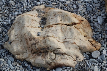 Big stone among the pebbles on the seashore.