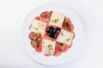 Veal carpaccio on white background close up top view. A traditional Italian dish.