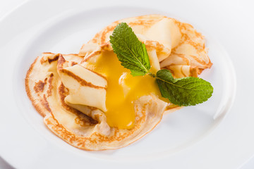 Two pancakes with honey on a white plate on a light background (close top view)