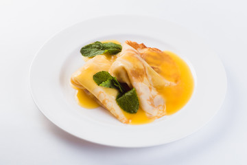 Two pancakes with honey on a white plate on a light background (close)