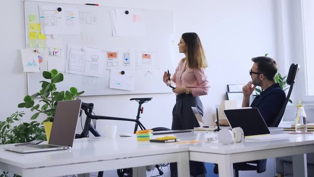 Two web designers discussing website mobile appl design on whiteboard