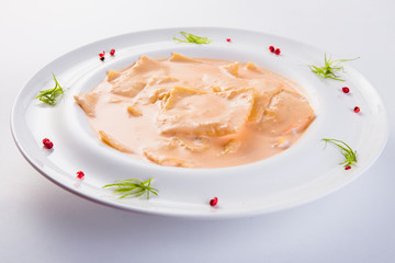 Ravioli stuffed on a white plate on a light background (close)