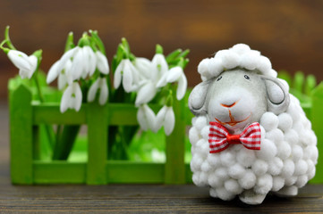 Easter decoration. Cute sheep figurine and spring flowers