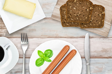 Top view of simple and energetic brakfast ( coffee, butter, dark bread, sausages) in rustic style on a wooden vintage table 