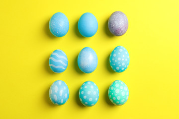 Flat lay composition with colorful easter eggs on yellow background. Top view