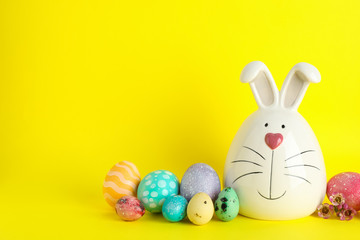 Decorated bunny and Easter eggs on color background. Space for text