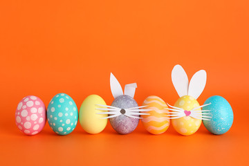 Decorated Easter eggs and cute bunny's ears on color background