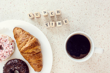 plate of baked sweets cup of coffee and lunch time letters on wooden bloks