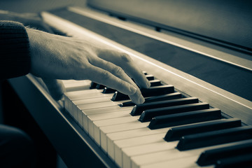 Hands of a man playing the electric piano.