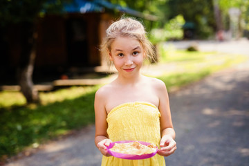 Blonde smiling girl with plate of pancakes in the country