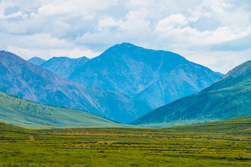 Obraz premium Spectacular view of giant mountains under cloudy sky. Huge mountain range at overcast weather. Wonderful wild scenery. Atmospheric dramatic highland landscape of majestic nature. Scenic mountainscape.
