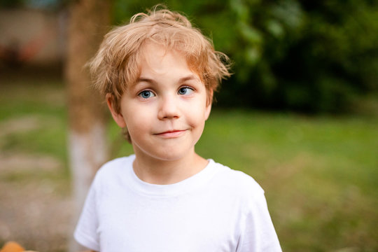 Blonde smiling boy with strabismus in warm park