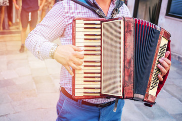 artist musician playing a melody on the accordion on a city street