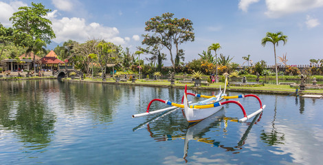 Panorama of a traditional Balinese fishing boat in the pond of the Taman Tirta Gangga water palace on Bali, Indonesia
