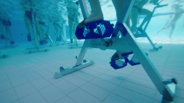 Close underwater shot of a man pedaling on an aqua bike in a swimming pool