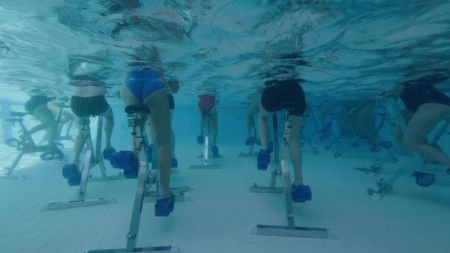 Behind view of women aqua biking in a swimming pool 