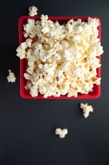 Popcorn in a red container on a white and black background. Snacks for the film.