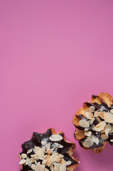 Sweet dessert eclairs profiteroles on a pink background.