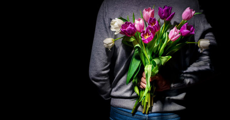 Man's hand hold bouquet of colorful tulips on dark background. Spring flowers for Mother's Day, International Women's Day, birthday