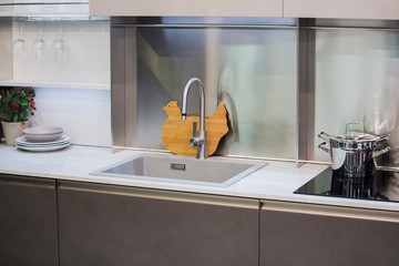 Kitchen faucet, modern gray kitchen in loft style, white table, luxury faucet kitchen